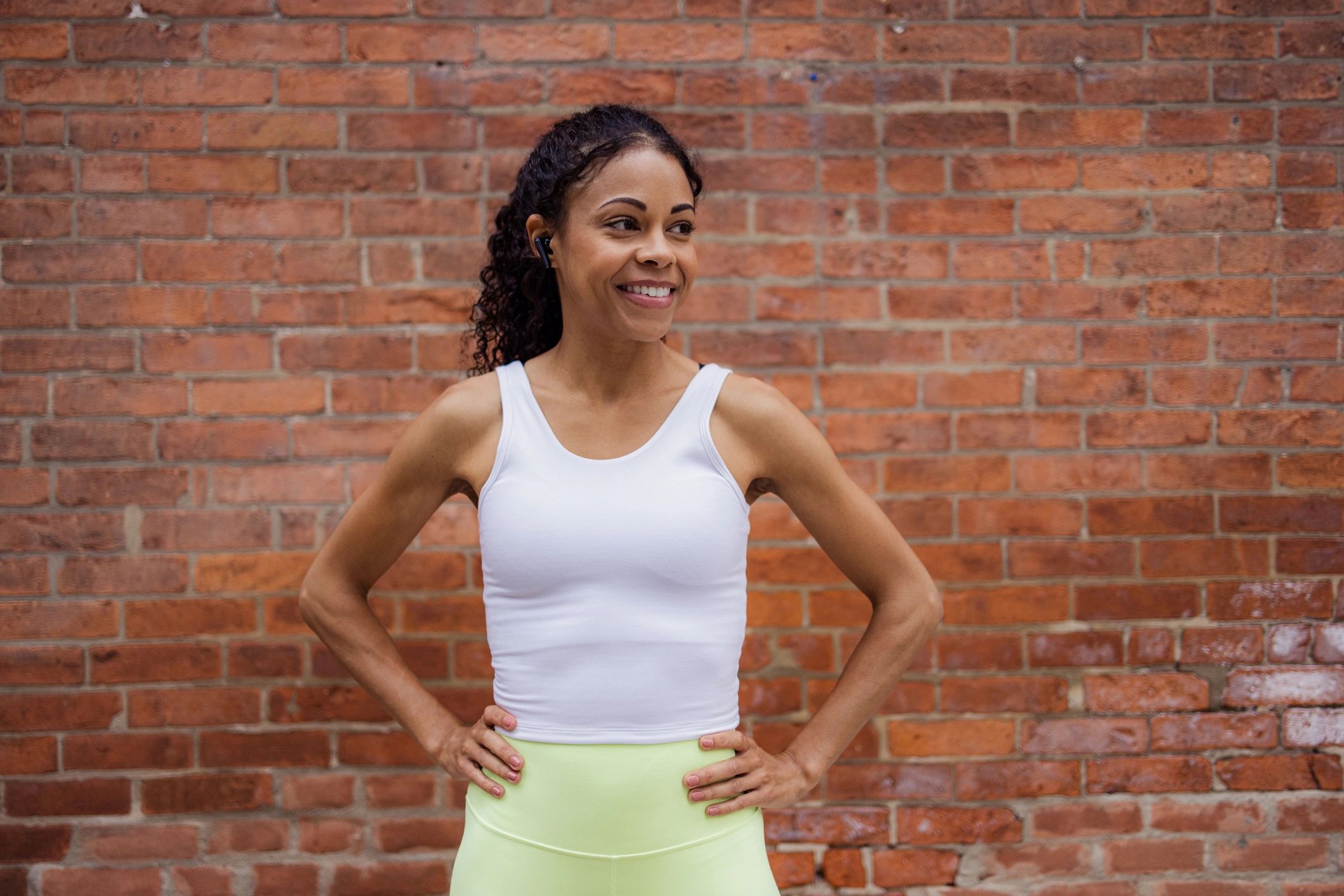 Customer in activewear smiling and listening to music outdoors